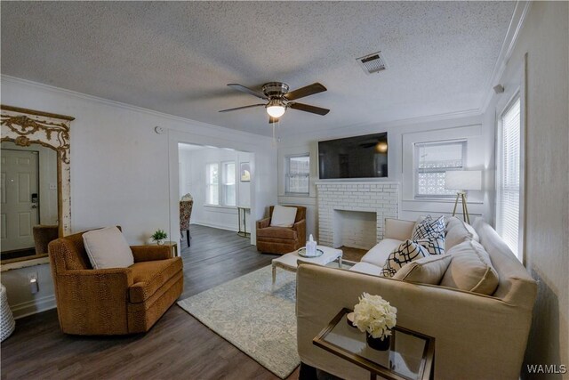 3216 34th Ave, Northport, AL 35476 - living room with ornamental molding, a ceiling fan, a textured ceiling, dark wood finished floors, and a brick fireplace