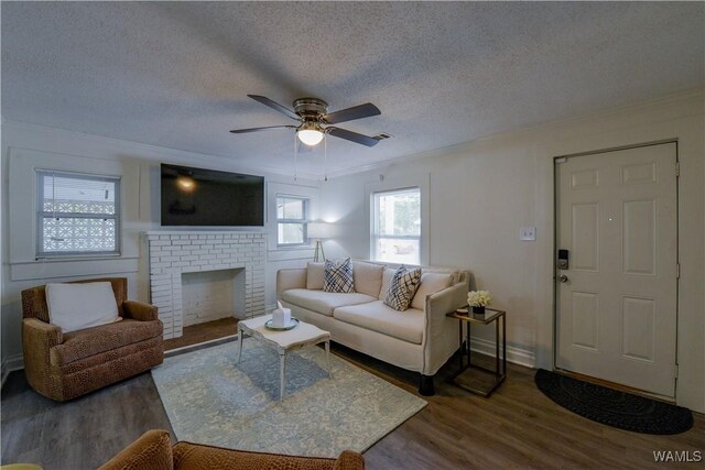 3216 34th Ave, Northport, AL 35476 - living room with crown molding, dark wood-type flooring, a textured ceiling, a ceiling fan, and a brick fireplace
