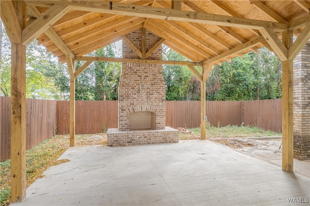 view of patio with an outdoor brick fireplace and a fenced backyard