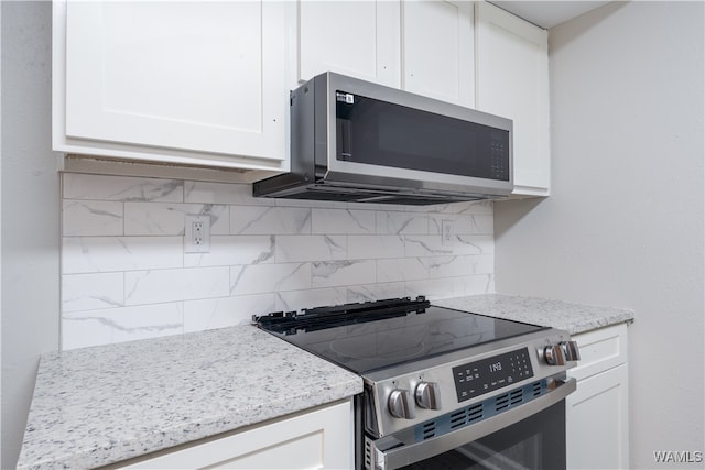 kitchen featuring stainless steel appliances, tasteful backsplash, white cabinetry, and light stone countertops