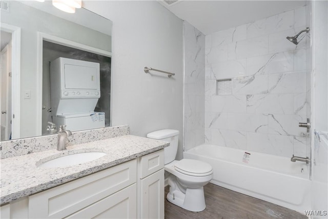 full bath featuring bathing tub / shower combination, stacked washer and dryer, toilet, vanity, and wood finished floors