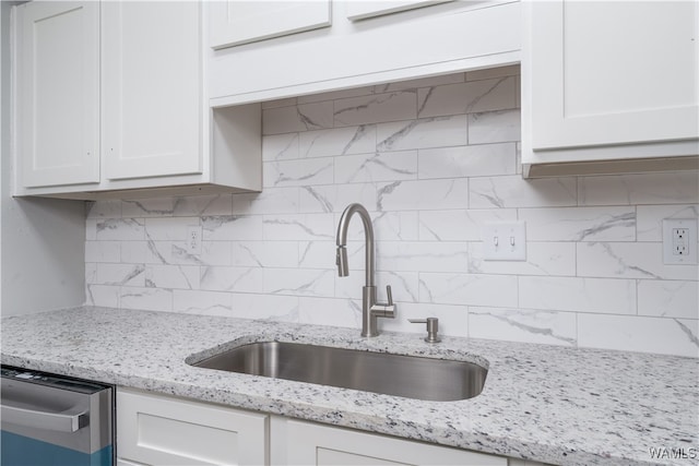 kitchen with tasteful backsplash, white cabinetry, a sink, and stainless steel dishwasher