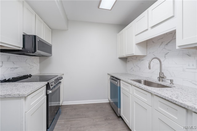 kitchen featuring baseboards, white cabinets, dishwasher, black electric range oven, and a sink