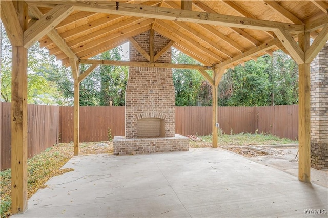 view of patio featuring an outdoor brick fireplace and a fenced backyard