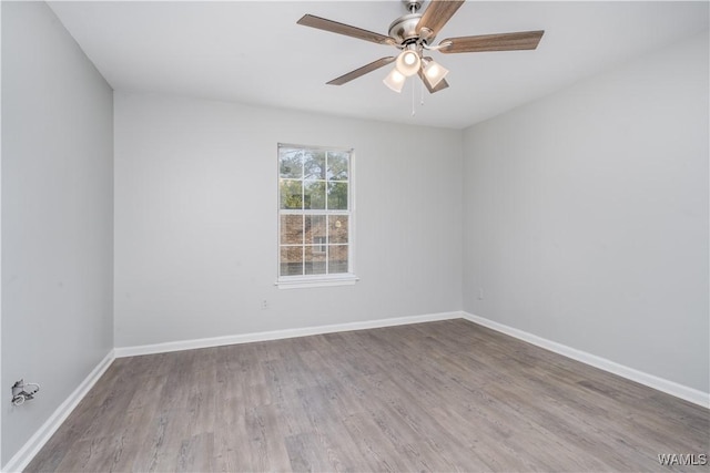 spare room featuring wood finished floors, a ceiling fan, and baseboards