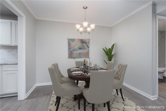 dining area with baseboards, crown molding, wood finished floors, and a notable chandelier