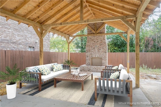 view of patio / terrace featuring a gazebo, a fenced backyard, and an outdoor living space with a fireplace