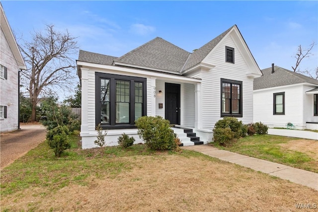 view of front of home with a front yard and roof with shingles