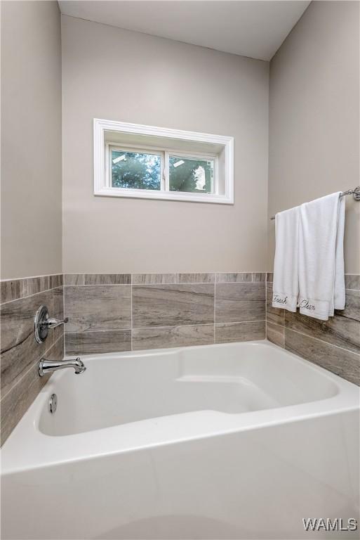 bathroom featuring a bathing tub, baseboards, double vanity, a sink, and a spacious closet