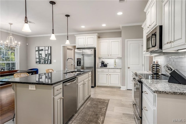 kitchen with a sink, stainless steel appliances, ornamental molding, and white cabinetry