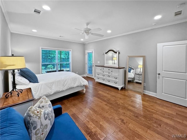 bedroom featuring wood finished floors, visible vents, and ornamental molding