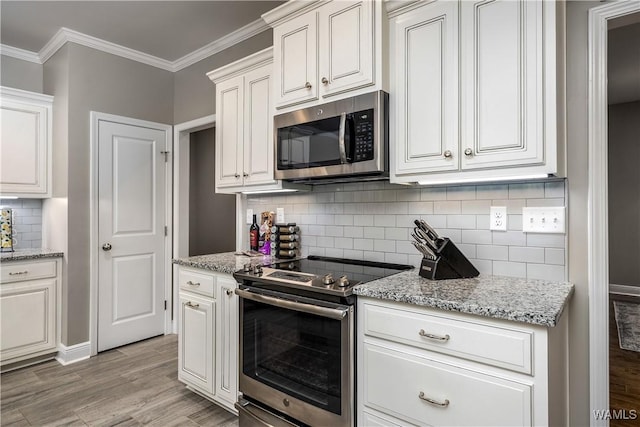 kitchen featuring backsplash, ornamental molding, light wood-style floors, white cabinets, and stainless steel appliances