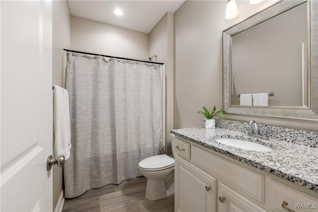 bathroom with a shower with shower curtain, toilet, wood finished floors, and vanity