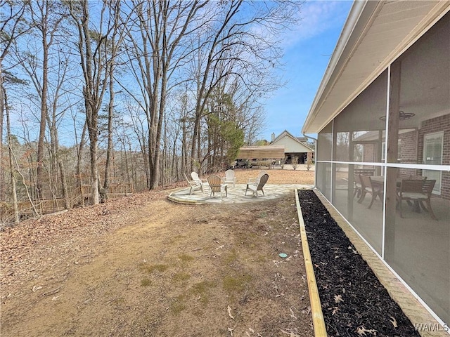 view of yard featuring a patio area, an outdoor fire pit, and a sunroom