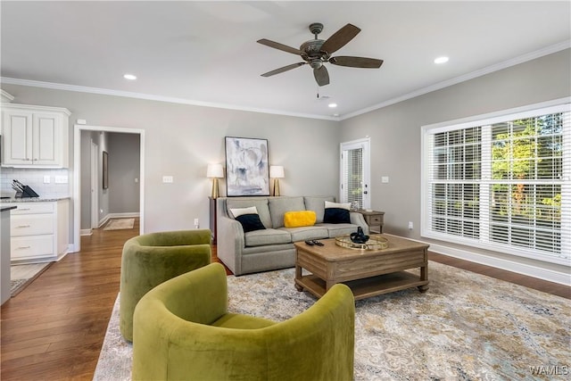 living area featuring ornamental molding, wood finished floors, recessed lighting, baseboards, and ceiling fan