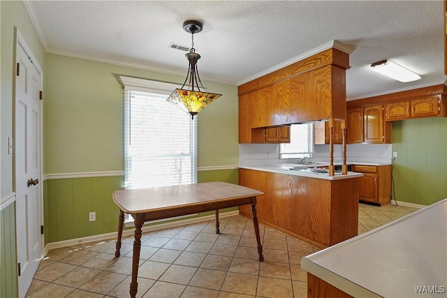 kitchen with pendant lighting, ornamental molding, kitchen peninsula, and light tile patterned floors