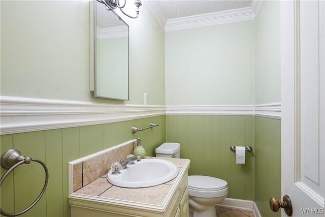 bathroom with tile patterned floors, toilet, a textured ceiling, ornamental molding, and vanity