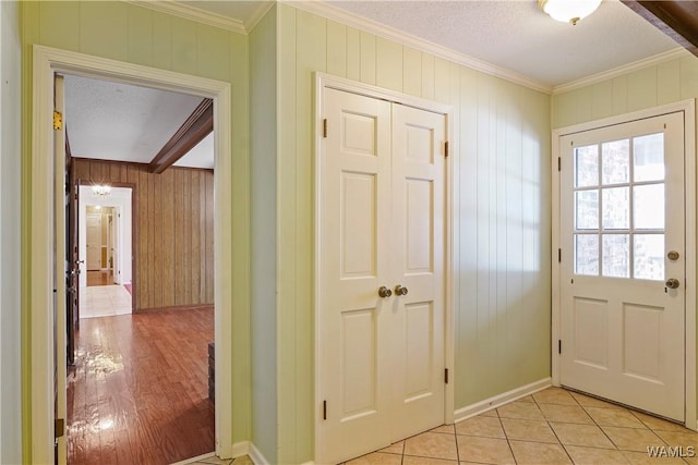 entryway featuring ornamental molding, a textured ceiling, and light tile patterned floors