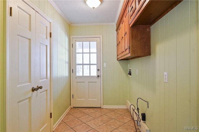 clothes washing area featuring cabinets, ornamental molding, washer hookup, and light tile patterned floors