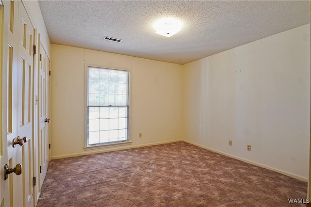 carpeted empty room with a textured ceiling