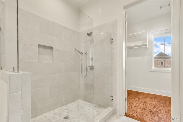 bathroom featuring wood-type flooring, a shower with shower door, and crown molding