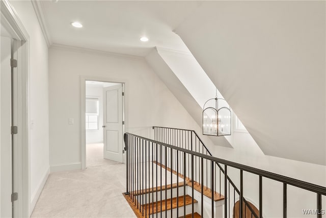 corridor with ornamental molding, light carpet, and an inviting chandelier