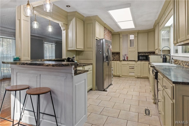 kitchen featuring cream cabinetry, appliances with stainless steel finishes, a breakfast bar area, and sink