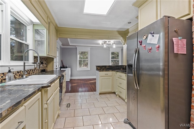 kitchen with sink, decorative backsplash, stainless steel fridge, cream cabinetry, and light tile patterned flooring