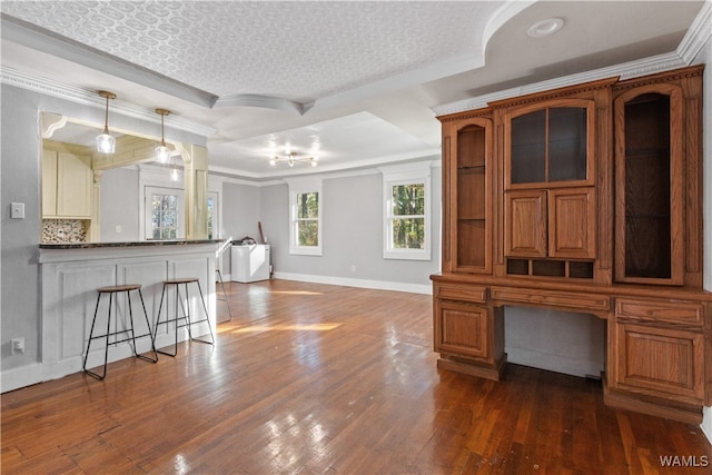 interior space featuring a textured ceiling, a raised ceiling, crown molding, dark wood-type flooring, and washer / dryer