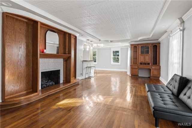 unfurnished living room with a textured ceiling, a tile fireplace, dark hardwood / wood-style floors, and ornamental molding