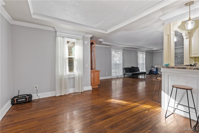 unfurnished living room featuring a textured ceiling, dark hardwood / wood-style flooring, a tray ceiling, and ornamental molding