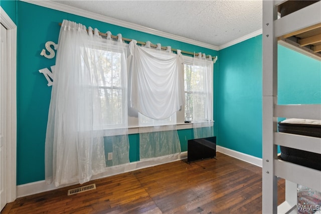 unfurnished bedroom featuring a textured ceiling, dark hardwood / wood-style floors, and ornamental molding