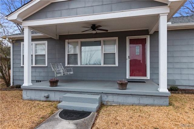 doorway to property featuring a lawn, ceiling fan, and a porch