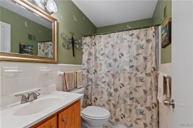 bathroom with vanity, toilet, a shower with shower curtain, and tile walls