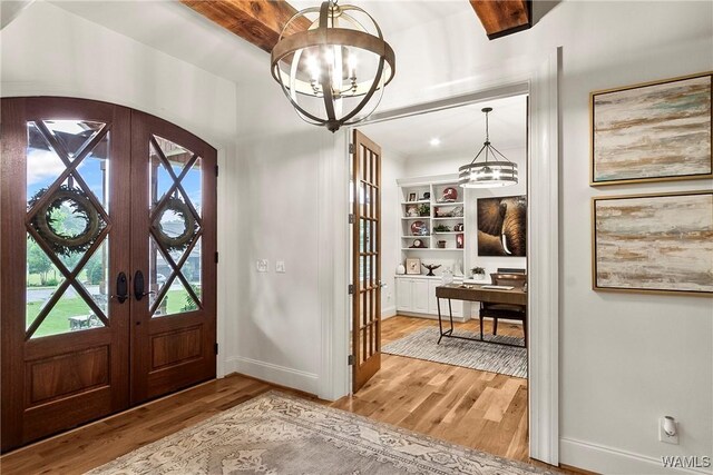 10300 Legacy Ln, Northport, AL 35475 - entrance foyer with french doors, a chandelier, light wood-style flooring, baseboards, and arched walkways