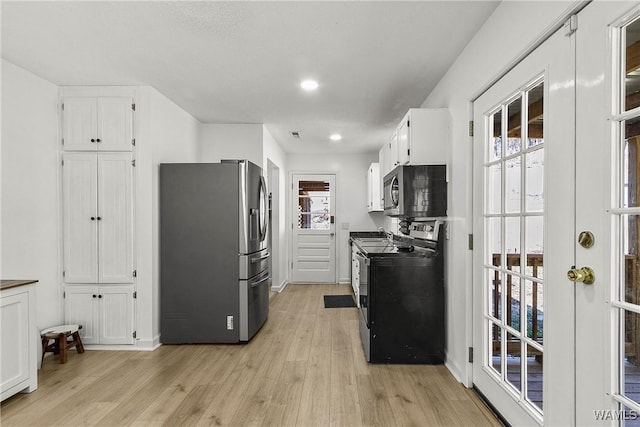 kitchen featuring light wood finished floors, appliances with stainless steel finishes, a wealth of natural light, and white cabinetry