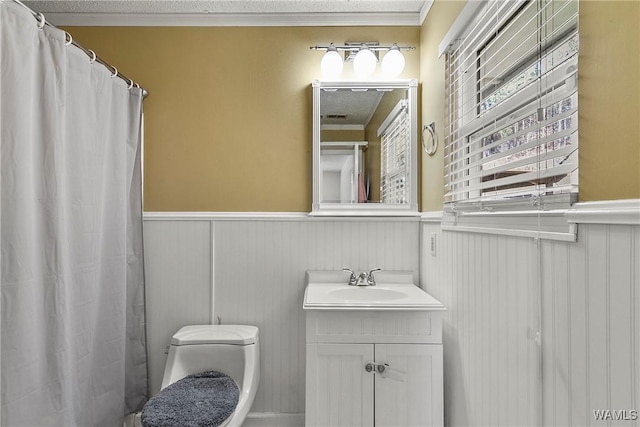 bathroom featuring curtained shower, toilet, a wainscoted wall, vanity, and crown molding