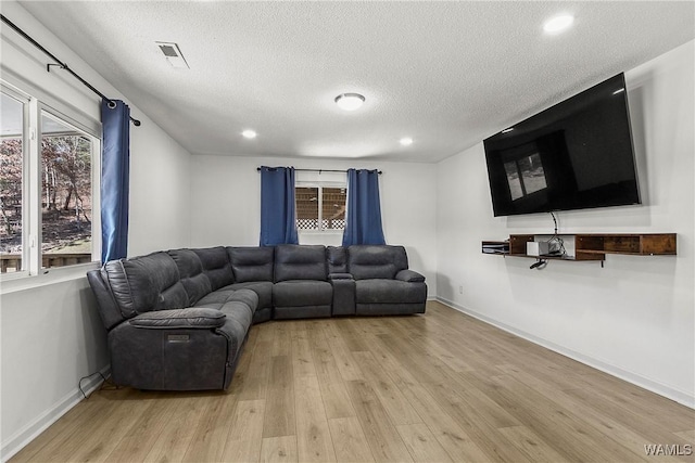 living area with light wood-style floors, baseboards, and visible vents