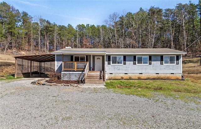 manufactured / mobile home featuring a porch, a forest view, driveway, crawl space, and a carport