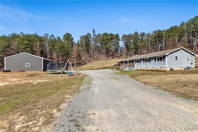 exterior space with crawl space, a trampoline, gravel driveway, and a front lawn