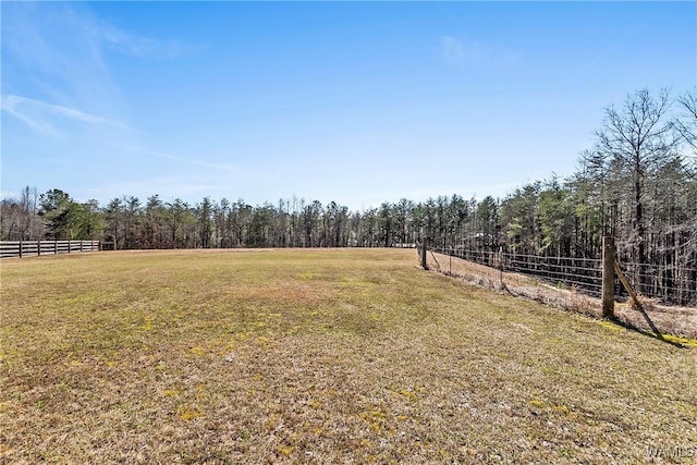 view of yard featuring a forest view, fence, and a rural view