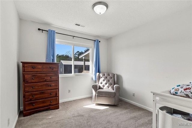 sitting room with baseboards, carpet, visible vents, and a textured ceiling