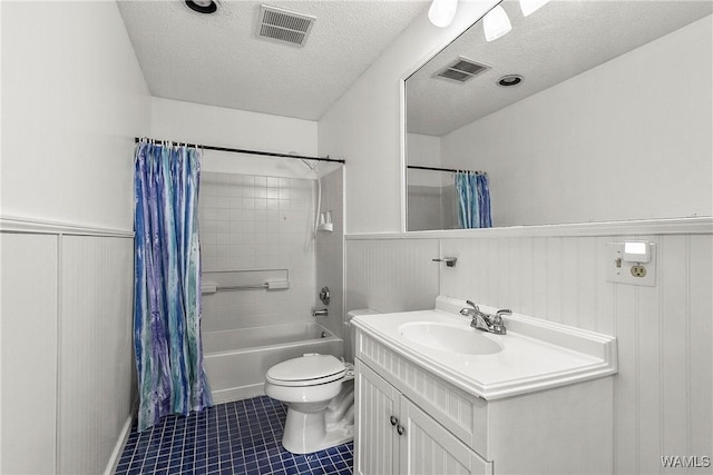 bathroom featuring a wainscoted wall, a textured ceiling, and visible vents