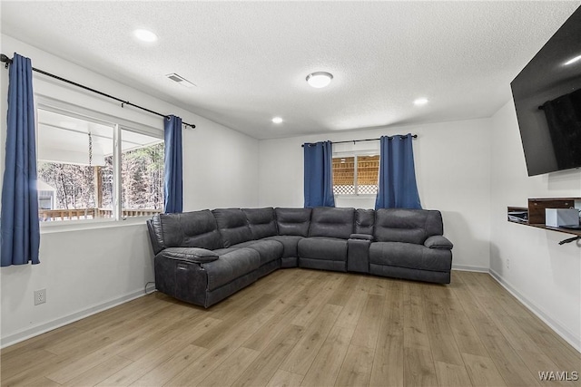 living area featuring light wood-style floors, visible vents, and a wealth of natural light