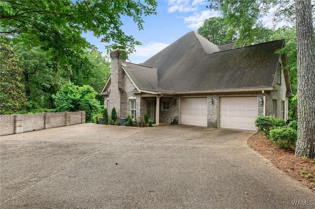 11147 Mountain Park Cir, Tuscaloosa, AL 35405 - view of front of house with driveway, a garage, a chimney, brick siding, and roof with shingles