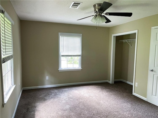 unfurnished bedroom featuring visible vents, a textured ceiling, carpet, and baseboards