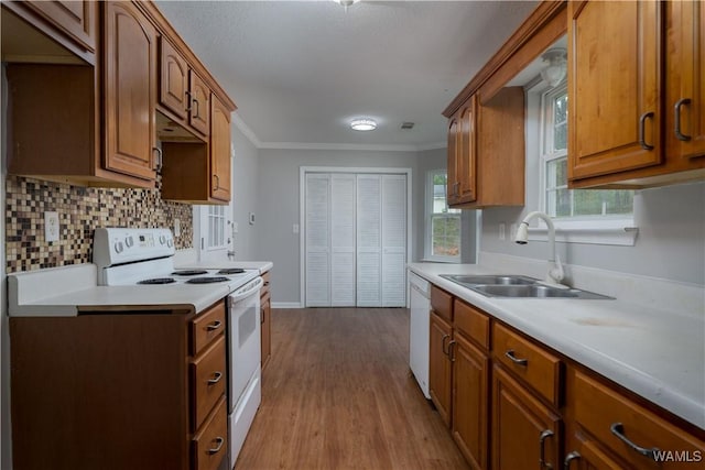 kitchen featuring wood finished floors, white appliances, light countertops, tasteful backsplash, and a sink