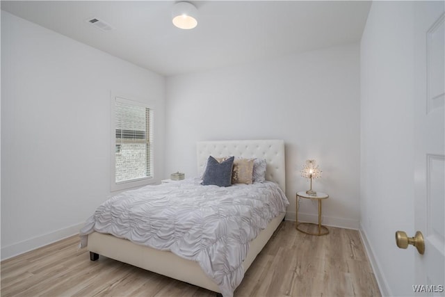 bedroom featuring light wood finished floors, visible vents, and baseboards