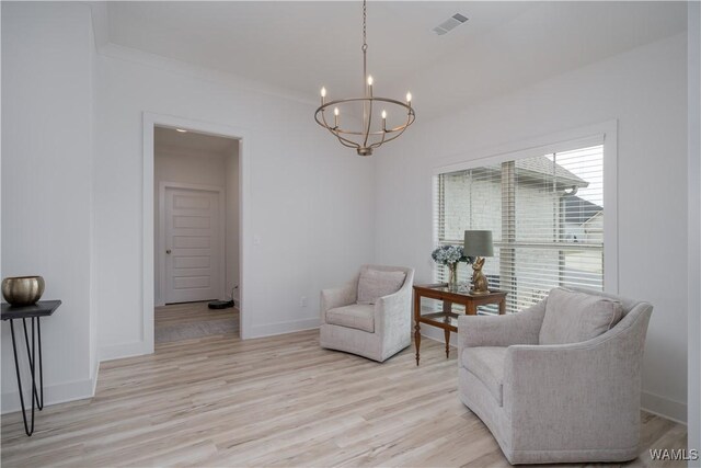 sitting room with light wood-style flooring, visible vents, baseboards, and a notable chandelier