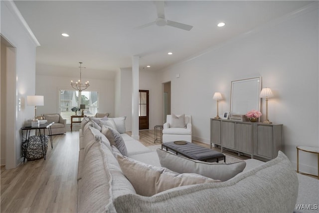 living area featuring light wood-style flooring, ceiling fan with notable chandelier, ornamental molding, and recessed lighting